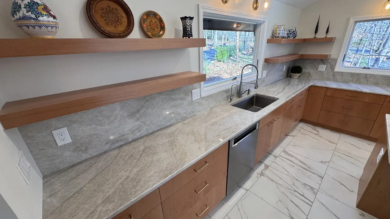 A kitchen with floating wood shelves, a marble-look backsplash and an undermount sink